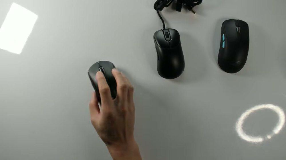 Overhead view of a hand gripping a mouse, with two other mice to the right