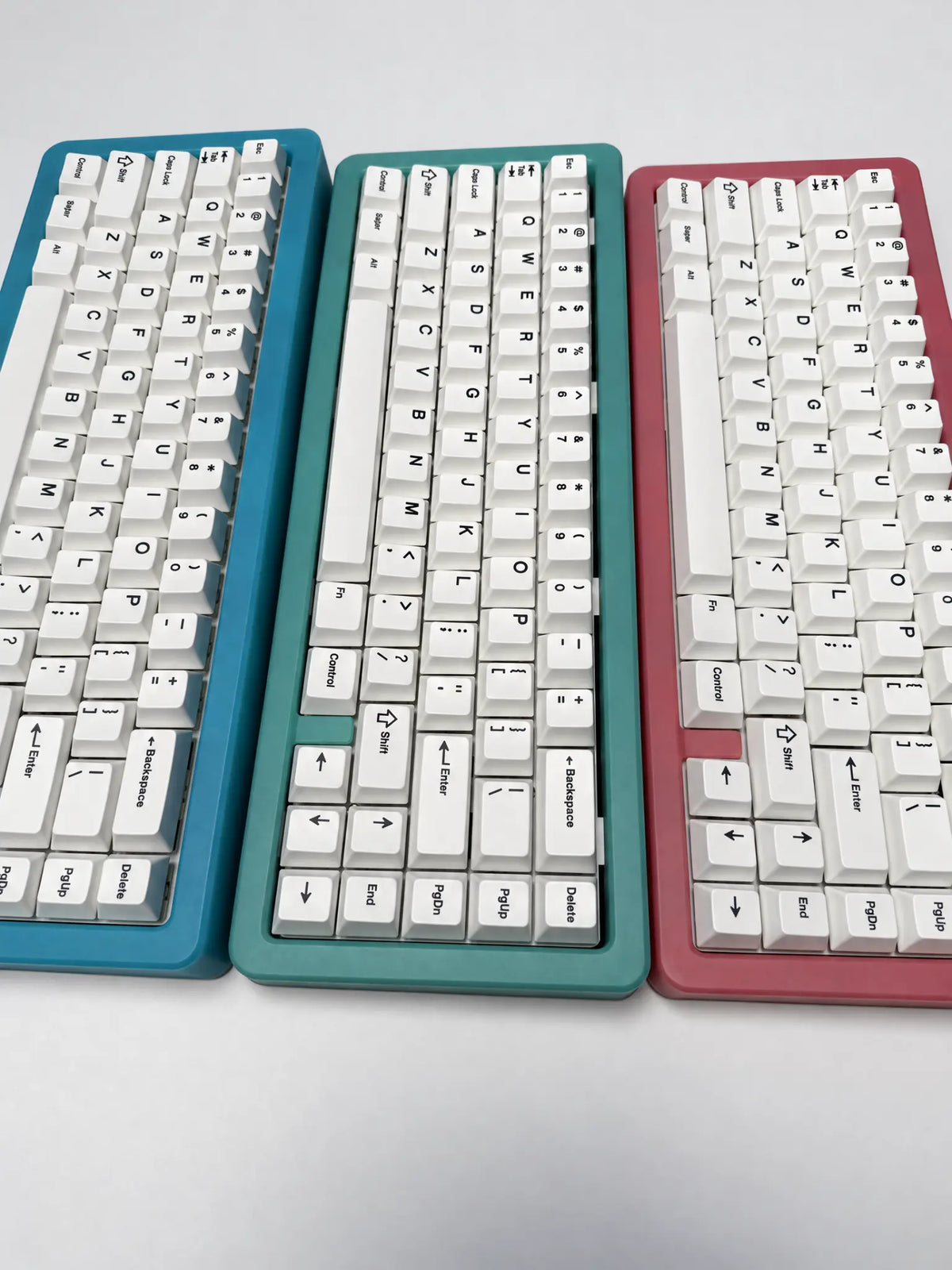 Odin Gaming Aurora65 LITE blue, green and pink keyboards side by side on a light background for color comparison.