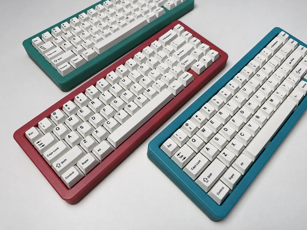 Odin Gaming Aurora65 LITE keyboards in pink, green and blue, arranged diagonally to compare the translucent case colors.
